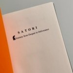 Open book page showing the title 'SATORI' and subtitle 'Journey from Despair to Deliverance' with an orange edge on the left.