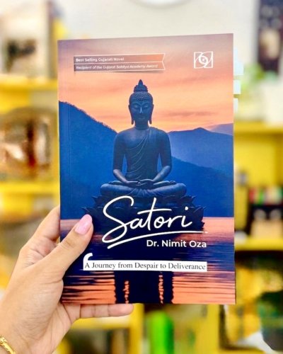 Front cover of a book titled 'Satori' by Dr. Nimit Oza, with the subtitle 'A Journey from Despair to Deliverance,' held in a left hand in a blurred bookstore background.